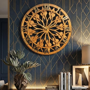 Peut inclure: Une grande horloge murale ronde dorée avec des chiffres romains et un motif floral décoratif. L'horloge est fixée sur un mur bleu foncé avec un motif géométrique doré. Un vase avec de la verdure et des livres sont en dessous.