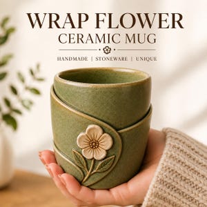 Pode incluir: Uma caneca de cerâmica verde com acabamento salpicado e um design envolvente com um relevo de flor de cor clara. O texto WRAP FLOWER CERAMIC MUG HANDMADE | STONEWARE | UNIQUE está impresso acima em letras castanho-escuras.
