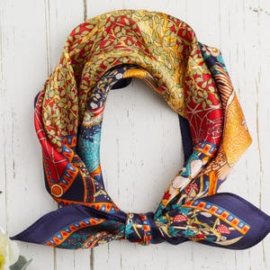 May include: A colorful silk scarf with a detailed pattern. The scarf features a mix of red, yellow, blue, and green hues. The scarf is tied in a knot, showcasing its intricate design and vibrant colors. The scarf is a fashion accessory.