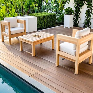 Puede incluir: Juego de muebles de exterior de madera clara, compuesto por dos sillones con cojines blancos y una mesa de centro a juego. El conjunto está colocado sobre una terraza de madera. Los muebles presentan un diseño moderno y funcional.