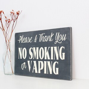 Może przedstawiać: Drewniany znak w kolorze szarym z białym napisem "Please & Thank You No Smoking or Vaping".