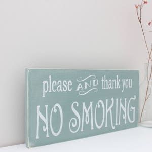 Puede incluir: Un letrero de madera azul claro con texto blanco que dice "please and thank you NO SMOKING".