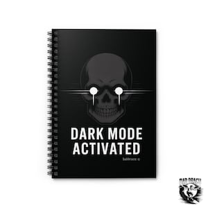 May include: Black spiral-bound notebook with a skull graphic and the text "DARK MODE ACTIVATED". The skull has glowing white eyes and is centered above the text. The notebook has a black cover.