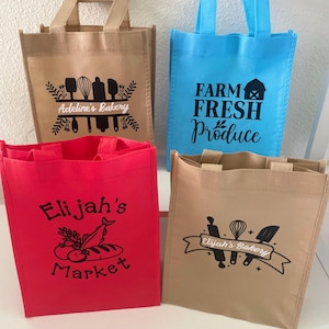 Può includere: Quattro borse tote riutilizzabili in beige, blu e rosso. Ogni borsa presenta un design diverso in nero, tra cui testo e illustrazioni. Le borse hanno manici e sono ideali per la spesa.