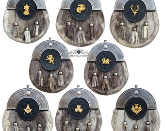 Könnte beinhalten: Eine Auswahl traditioneller schottischer Sporrane mit verschiedenen Emblemen. Jeder Sporran hat einen silberfarbenen Metallaufsatz, eine schwarze Lederbasis und einen Pelzkörper. Quasten hängen von unten. Die Embleme umfassen einen Hirsch, einen Löwen und ein Kleeblatt.