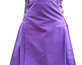 Könnte beinhalten: Ein leuchtend violetter Kilt mit einem plissierten Design. Er verfügt über verstellbare Riemen mit silberfarbenen Schnallen und ein dekoratives Emblem in der Nähe des Saums. Der Stoff hat einen leichten Glanz und der Kilt scheint aus einem strapazierfähigen Material zu sein.