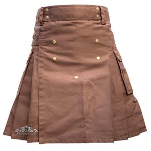 May include: Brown kilt with pleats, pockets, and gold-colored button details. The kilt features a structured waistband with belt loops and decorative metal accents. The kilt has the text "MEN KILT SHOP" on the bottom left.