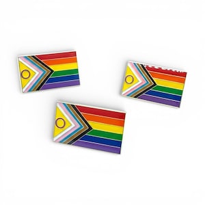 Può includere: Tre spille rettangolari in smalto con un design a bandiera arcobaleno, con i colori della bandiera del Pride LGBTQ+. Ogni spilla ha un bordo argentato e include i colori della bandiera Progress Pride, con un cerchio giallo.