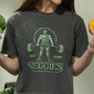 Funny Veggie Gym T-Shirt – “Eat Your Veggies” Retro Strongman Tee | Plant Based Fitness Shirt | Vegetarian Gift | Eco Workout Graphic Tee