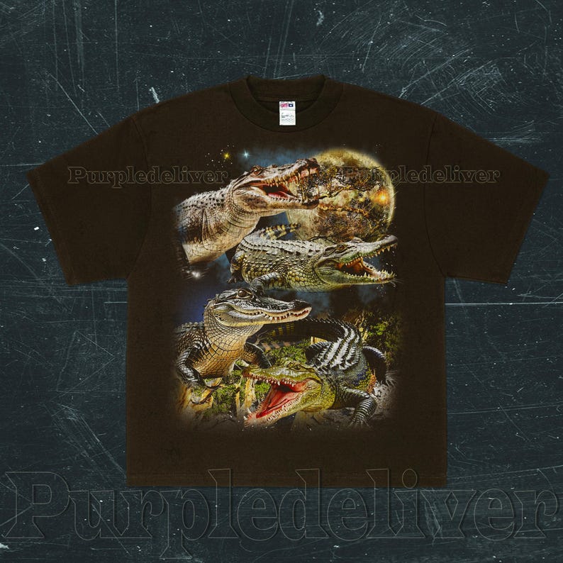 May include: Brown t-shirt featuring a detailed graphic of several alligators with open mouths, set against a backdrop of a full moon and starry sky. The design showcases the alligators in various poses, highlighting their textures and colors.