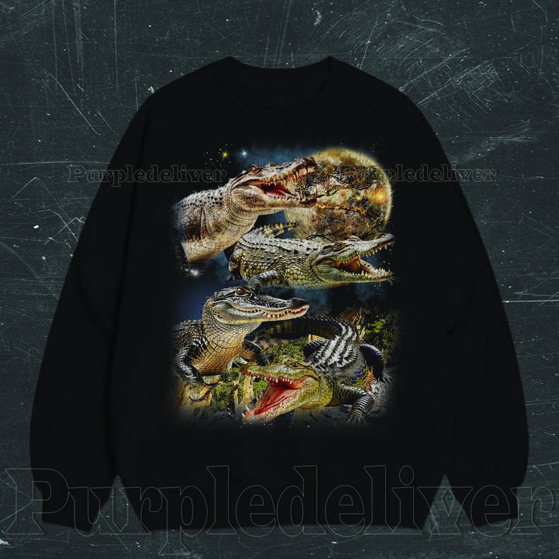 May include: Black sweatshirt featuring a detailed graphic of several alligators with open mouths, set against a backdrop of a full moon and starry sky. The design showcases the alligators in various poses, highlighting their textures and colors.