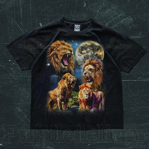 May include: Black t-shirt featuring a vibrant graphic of four lions with open mouths, set against a night sky with a full moon. The lions are depicted in shades of brown and orange, creating a striking contrast.