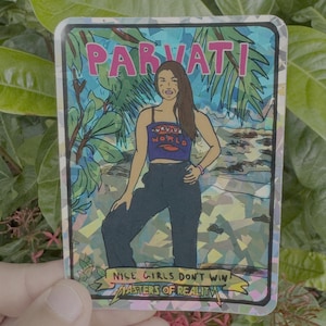 May include: A holographic trading card featuring an illustration of a woman named Parvati. The card has a blue and green background with palm trees and water. Text on the card includes "PARVATI", "DAUGHTER WORLD", and "NICE GIRLS DON'T WIN MASTERS OF REALITY".