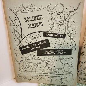 May include: Vintage printed program titled "SOLDIER SHOWS" with "BROADWAY SPECIAL" and "THE HASTY HEART" text. The cover is light beige with black text and decorative lines and shapes. The program is Folio No. 28, prepared by the Special Services Division.