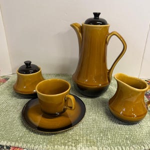 May include: A trio of ceramic mugs with a speckled, matte finish in cream, light grey, and dark grey. Each mug features a simple, minimalist design, ideal for tea or coffee.