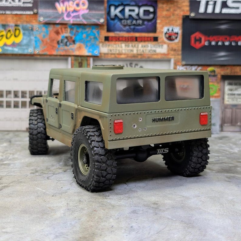 Puede incluir: Un modelo detallado de Hummer verde oliva con neum&aacute;ticos negros grandes. El modelo tiene la palabra "HUMMER" impresa en la parte trasera. El modelo tiene una apariencia robusta con detalles visibles como ventanas y luces traseras.
