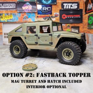 Puede incluir: Un Hummer de juguete verde oliva con neum&aacute;ticos negros y una torreta de cargador. El texto "OPTION #2: FASTBACK TOPPER MAG TURRET AND HATCH INCLUDED INTERIOR OPTIONAL" se muestra debajo. Una pieza circular separada est&aacute; frente al Hummer.