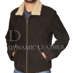 Può includere: Giacca in pelle scamosciata marrone scuro con colletto in montone color crema. La giacca ha una chiusura con zip, due tasche anteriori e il testo "DYNAMIC LEATHER" stampato.