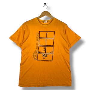 Puede incluir: Camiseta naranja con un dise&ntilde;o gr&aacute;fico de "Pesadilla antes de Navidad" de Tim Burton. El dise&ntilde;o incluye paneles rectangulares negros con im&aacute;genes de Jack Skellington. El texto "Tim Burton's Nightmare Before Christmas" est&aacute; impreso verticalmente.