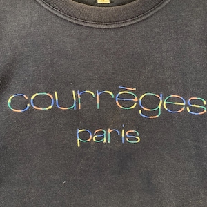 May include: A navy blue sweatshirt with the embroidered text "courr&egrave;ges paris" in a rainbow color scheme. The text is centered on the chest of the sweatshirt. The sweatshirt has a crew neck.