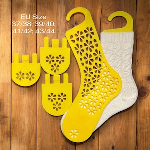 May include: A pair of cream cable knit socks with yellow sock shapers. The yellow shapers have a floral design and are in various sizes. The text "EU Size 37/38; 39/40; 41/42; 43/44" is visible.