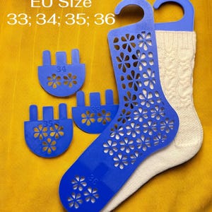 Puede incluir: Calcetines blancos de punto trenzado con hormas azules. Las hormas tienen un diseño floral recortado y están marcadas con las tallas 33, 34, 35 y 36. También se ve el texto "EU Size".