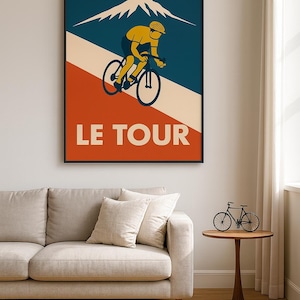 May include: A framed poster with a vintage cycling theme. The artwork features a cyclist in yellow and black riding a bicycle against a backdrop of a mountain and the text "LE TOUR" in white. The poster is framed in black.