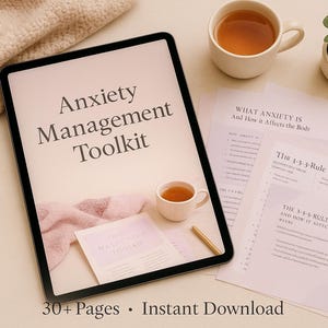 Könnte beinhalten: Ein Tablet zeigt "Anxiety Management Toolkit". Das Bild enthält zwei kleine weiße Teetassen mit Tee, bedruckte Seiten, eine kleine Topfpflanze und eine weiche Decke. Der Text "30+ Pages • Instant Download" ist ebenfalls sichtbar.