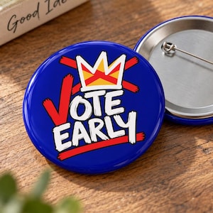 May include: A round blue pinback button featuring a white crown graphic and the text VOTE EARLY in bold white letters. The design includes red brushstroke accents behind the text and crown. The back shows a silver metal pin mechanism.