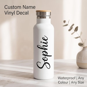 Peut inclure: Une bouteille d'eau blanche avec un goulot argenté et un bouchon en bois clair. Le prénom Sophie est imprimé verticalement en lettres cursives noires sur le devant. Le texte sur l'image indique Custom Name Vinyl Decal, Waterproof, Any Colour, Any Size.