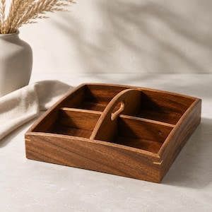 May include: A square wooden serving tray with a rich brown finish and visible wood grain. The tray is divided into four equal compartments by intersecting partitions and features a central vertical handle with a cutout for easy carrying.