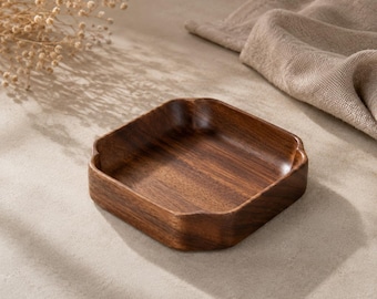 May include: A square wooden tray with rounded corners and a deep, dark brown wood grain finish. The tray features a smooth, polished surface with slightly raised edges, showcasing the natural texture and rich color variations of the wood.