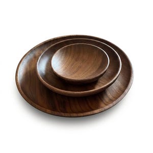 May include: A white ceramic mug with a black handle and the text "But First, Coffee" in a bold, black font. The mug is set against a neutral background, highlighting its simple design.