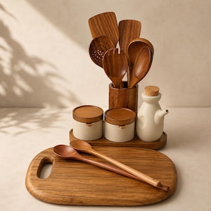May include: A kitchen set featuring a wooden cutting board, two wooden spoons, a wooden utensil holder with various wooden cooking tools, two small ceramic jars with wooden lids, and a ceramic oil cruet with a cork stopper on a wooden tray.