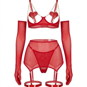 May include: A red lingerie set featuring a bra with heart-shaped accents and gold chain straps, a garter belt, a thong, and sheer gloves. The set is made of a sheer, lightweight material.