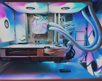 May include: A white computer case interior featuring an ASUS GeForce RTX graphics card, a liquid cooling system with white tubes, and multiple RGB fans emitting a soft glow. The motherboard is white with visible components and white cable management.