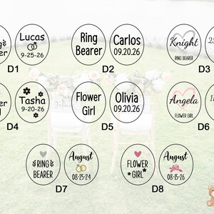 May include: A collection of circular wedding favor tags with various names, dates, and roles like "Ring Bearer" and "Flower Girl." Each tag features decorative elements such as hearts, flowers, and wedding rings. The tags are in black and white.