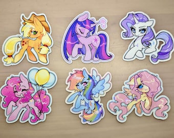 May include: Six die-cut stickers featuring cartoon ponies in various colors. The top row shows an orange pony with a hat, a purple pony with a horn, and a white pony with a purple mane. The bottom row shows a pink pony with balloons, a blue pony with wings, and a yellow pony with a pink mane.