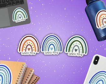 May include: Rainbow-themed stickers with the text "Genesis 9:13-16" are displayed on a laptop, water bottle, and phone. Three stickers are centered, featuring brown, blue, and green arches with heart details. The background is a purple surface with stars.