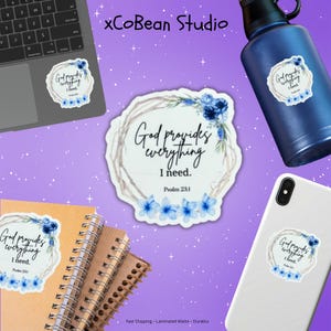 Puede incluir: Pegatinas blancas con el texto "God provides everything I need. Psalm 23:1" se muestran en un portátil, una botella de agua y un teléfono. Las pegatinas presentan un diseño de corona floral con flores azules. La imagen también incluye cuadernos.