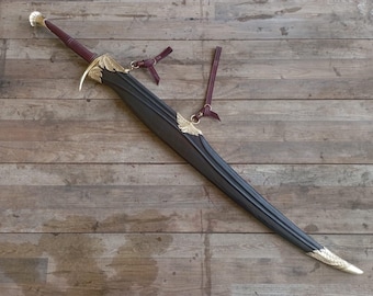 Puede incluir: Una espada con empuñadura envuelta en cuero color granate oscuro y una vaina a juego. La guarda, la boca de la vaina y la contera presentan adornos de metal dorado con grabados en forma de hoja. Incluye dos correas de cuero granate.