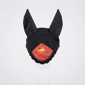 May include: A black horse ear bonnet featuring a crocheted main section, two tall fabric ears, and a central diamond-shaped patch in a gradient of orange and red. The edges are finished with a decorative twisted cord trim in matching black.