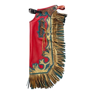 May include: A red leather chap featuring intricate brown floral tooling at the top, teal leather accents, and metallic gold leather overlays. The side is adorned with long, layered metallic gold and teal fringe, and it includes a black buckle strap.