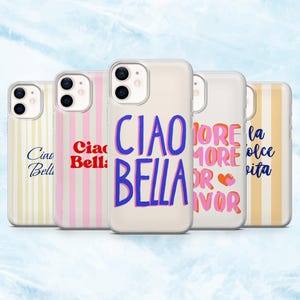 Op de afbeelding: Een verzameling doorzichtige telefoonhoesjes met diverse ontwerpen. Eén hoesje heeft de woorden "Ciao Bella" in blauw en roze. Andere hoesjes hebben streepjespatronen en zinnen als "More More Or Favor" en "La Dolce Vita".