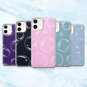 Può includere: Cinque cover per smartphone disposte in fila, ognuna con un colore di sfondo distinto tra cui viola scuro, nero, rosa, verde acqua e azzurro. Ogni cover presenta un motivo ripetuto di bolle con contorno bianco e piccoli accenti a stella.