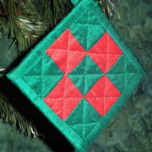 Può includere: Un ornamento natalizio trapuntato a forma di diamante. L'ornamento presenta un motivo di quadrati rossi e verdi, un bordo verde e un anello per appenderlo. L'ornamento è largo circa 10 cm.