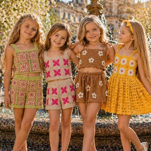 Könnte beinhalten: Vier junge Mädchen in handgefertigten Häkel-Outfits. Die Outfits umfassen Shorts und Crop-Tops in Grün, Rosa und Braun sowie ein gelbes Kleid. Die Outfits weisen Blumen- und geometrische Muster auf. Die Mädchen stehen vor einem Brunnen.