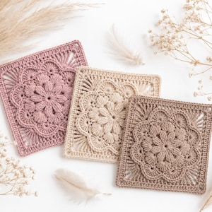 Peut inclure: Trois motifs carrés au crochet présentant un motif floral central avec des pétales rayonnants et une bordure géométrique. Les motifs sont de couleur vieux rose, crème et taupe, mettant en valeur un travail de fil complexe.