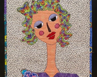 May include: A quilted artwork featuring a stylized face with a butterfly headdress. The face has rosy cheeks, red lips, and black eyes. The background is white with a black dotted pattern, and the border is blue and patterned.