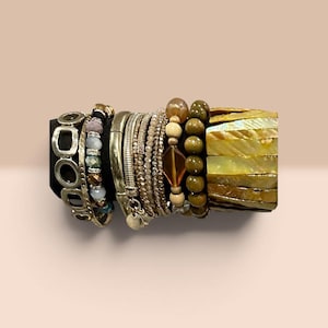 Peut inclure: Une collection de bracelets empilés présentant une variété de textures et de matériaux. L'ensemble comprend des maillons en métal argenté, des perles à facettes multicolores, de fines chaînes métalliques, des perles en bois rondes et lisses.